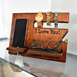 May include: Wooden organizer with slots for a watch, glasses, and a phone. It has a shelf for jewelry and the words "I Love You!" are engraved on the front.