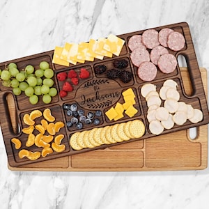 Walnut wood charcuterie board Sitting on top of a Red Oak Charcuterie with a white background 
With
Blueberries, raspberries, Oranges, Ham and Cheese spread out on top