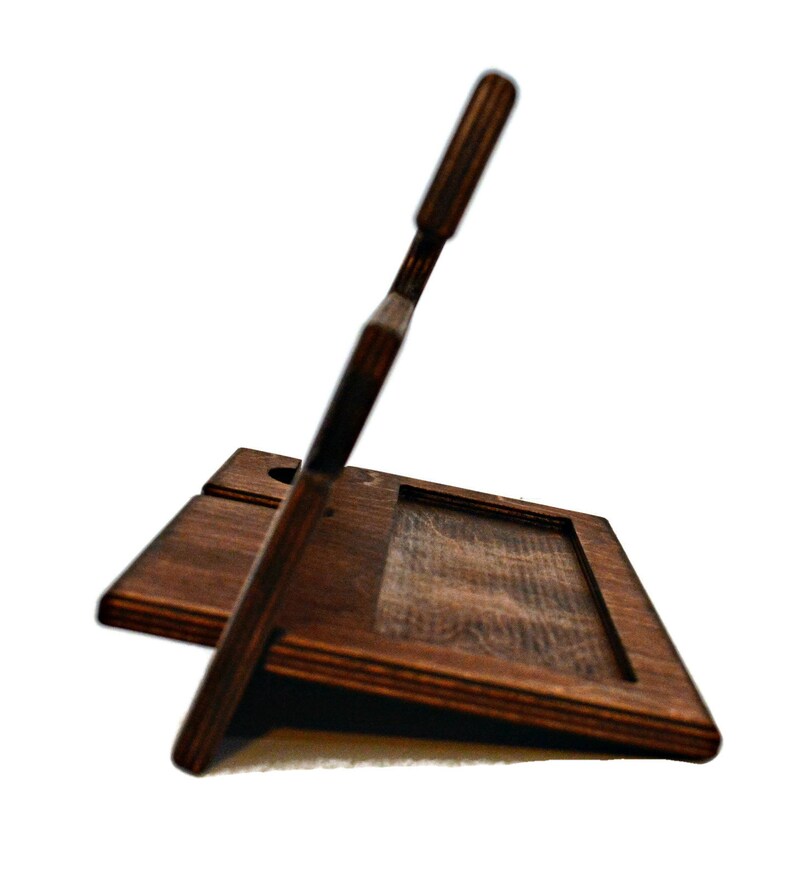 May include: A dark brown wooden phone stand with a slot for charging cables. The stand has a raised back to prop up a phone or tablet.