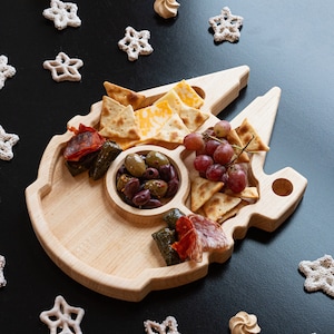 Wooden Millennium Falcon Shaped Tray with 5 compartments with appetizers in each one. Wood is light and sitting on a black backdrop.