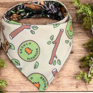 Puede incluir: Un pañuelo beige con un estampado verde y marrón de ramas, hojas y el texto "Branch Manager".