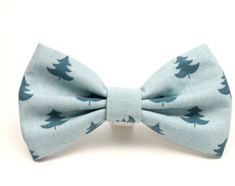 Puede incluir: Una pajarita azul claro con un patrón de árboles de Navidad azul oscuro.