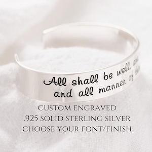 May include: A silver bangle bracelet with the inscription "All shall be well and all manner of things shall be well" engraved on it. The bracelet is made of .925 solid sterling silver and is customizable with different fonts and finishes.