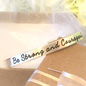 May include: Silver bracelet with the inscription "Be Strong and Courageous".