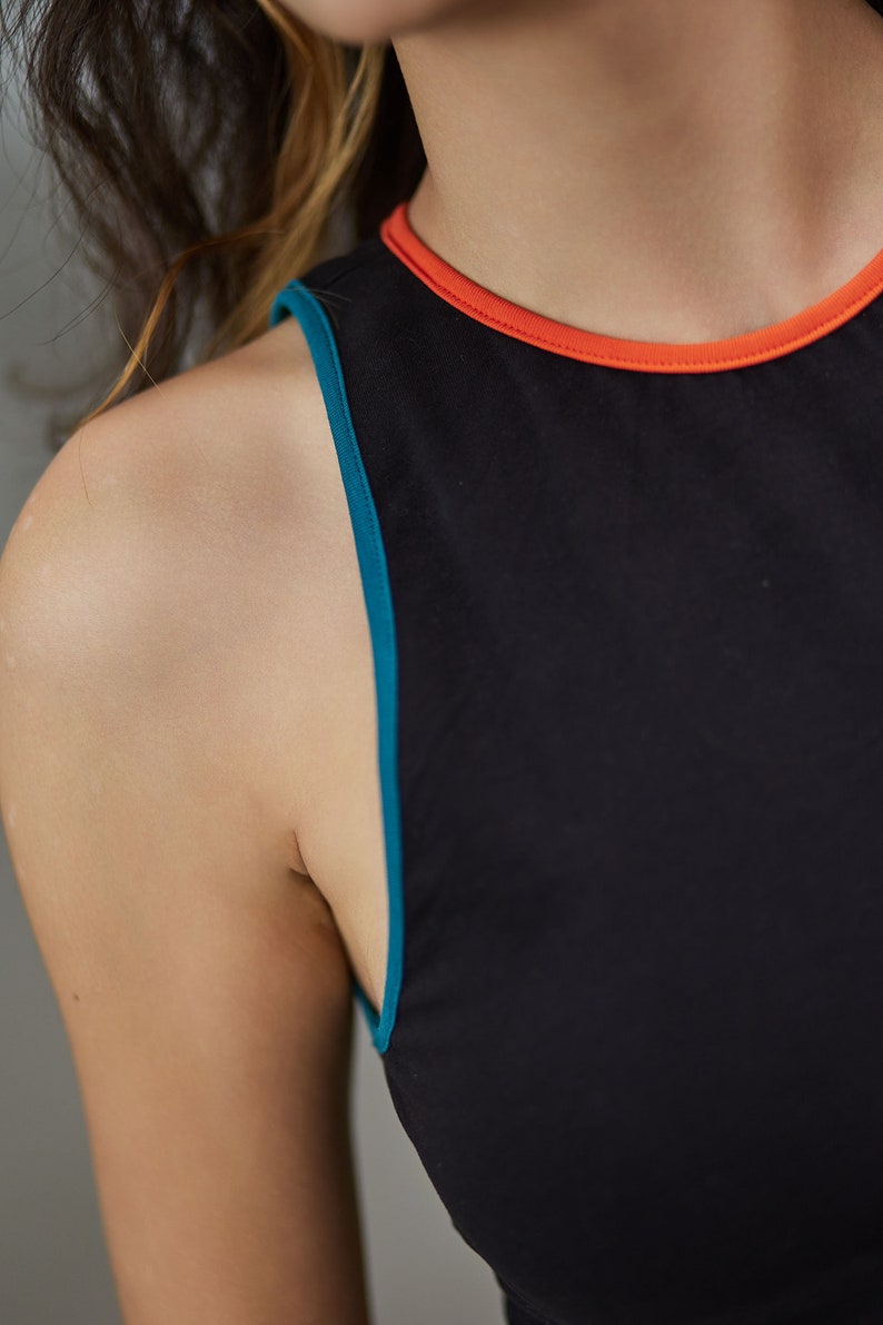 May include: A black sleeveless top with a teal and orange trim around the neckline.