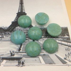 May include: Seven turquoise cabochon stones with a marbled pattern. The stones are round and have a smooth, polished surface.