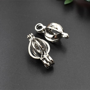 Peut inclure: Deux cages en métal argenté pour contenir de petits objets, comme des perles ou des breloques. Les cages sont ouvertes en haut et ont une boucle pour les attacher à une chaîne ou un bracelet.