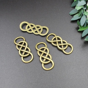 Pode incluir: Quatro pingentes de metal dourado antigo em forma de nó infinito. Os pingentes são intrincadamente detalhados e têm uma superfície ligeiramente texturizada.