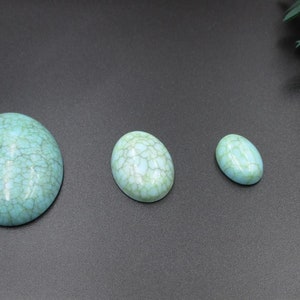 May include: Four oval-shaped turquoise cabochons of varying sizes. The cabochons have a light blue colour with a white marbled pattern.