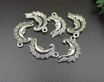 May include: Six silver-toned metal charms shaped like crescent moons with a face on each moon. The charms have a detailed design with small beads and leaves.