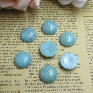 May include: Assortment of turquoise blue cabochon stones with a crackled finish. The stones are round and have a smooth, glossy surface.