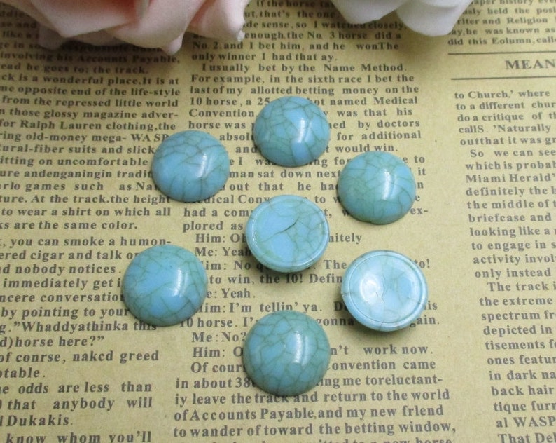 May include: Assortment of turquoise blue cabochon stones with a crackled finish. The stones are round and have a smooth, glossy surface.