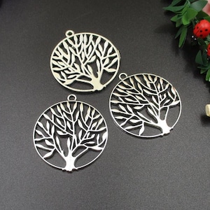 May include: Three silver metal tree of life charms with intricate designs. The charms are round and have a hole at the top for hanging.