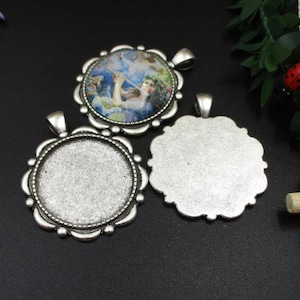 May include: Three silver-toned pendant trays with scalloped edges. One tray features a colorful image of a woman playing a flute. The other two trays are blank.