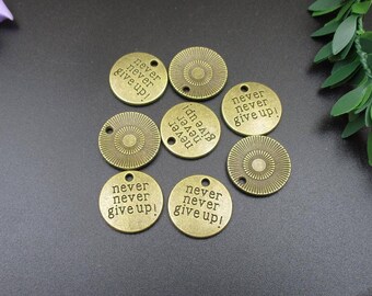 May include: A set of ten antique gold-toned metal charms with the phrase "never never give up!" engraved on each charm.