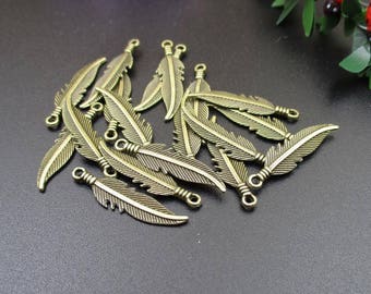Puede incluir: Un grupo de 15 abalorios de plumas de metal de color dorado antiguo con un bucle en la parte superior para sujetar a joyas o manualidades.
