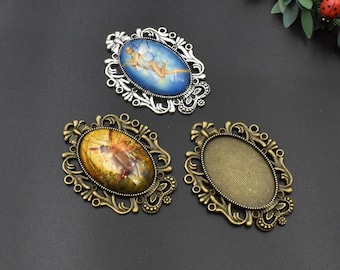 Puede incluir: Tres marcos de metal adornados con inserciones de vidrio ovaladas. Los marcos son plateados y bronce con diseños intrincados. Un marco tiene una imagen colorida de un hada dentro.