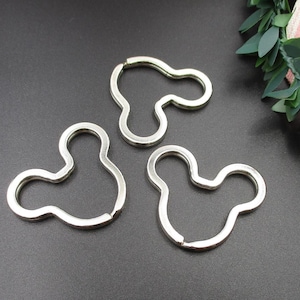 May include: Three silver keychains shaped like Mickey Mouse heads.