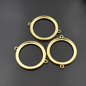 Op de afbeelding: Drie ronde metalen frames in goudkleur met een gladde afwerking. Elk frame heeft een kleine lus aan de bovenkant om op te hangen.