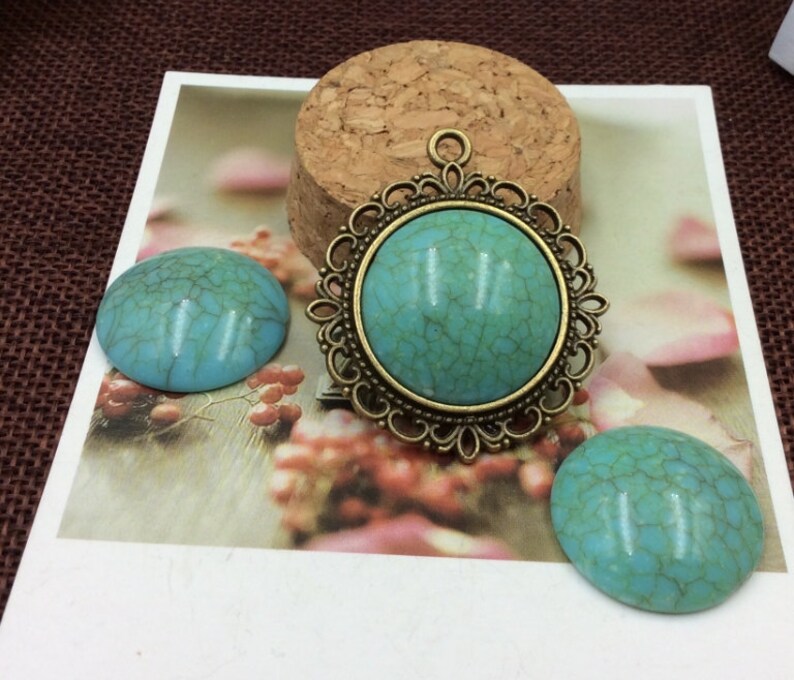 May include: Three turquoise cabochons, one with an ornate bronze frame, ready for jewellery making.
