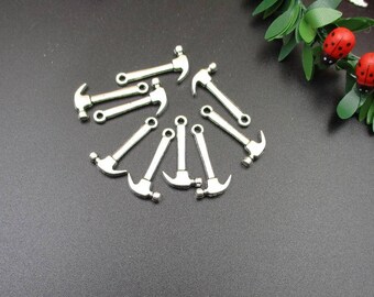 May include: A group of ten silver-toned hammer charms. The charms are all the same size and shape, and they have a loop at the top for attaching to a chain or bracelet.