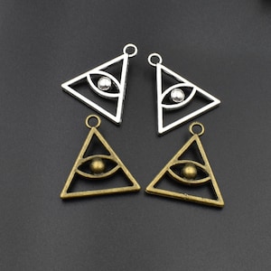 May include: Four silver and gold triangle charms with an all-seeing eye design. The charms have a loop at the top for attaching to jewelry.