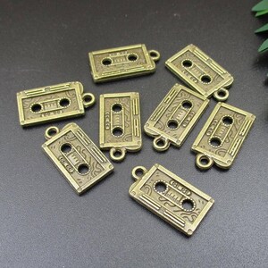 Puede incluir: Una colecci&oacute;n de ocho abalorios de metal dorado antiguo con forma de cintas de casete. Los abalorios tienen un aspecto vintage y son perfectos para a&ntilde;adir un toque de nostalgia a las joyas o las manualidades.