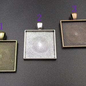 May include: Three square pendant trays in antique bronze, silver, and copper tones. Each tray has a loop at the top for a chain and a decorative pattern inside. The trays are empty, ready for customisation.