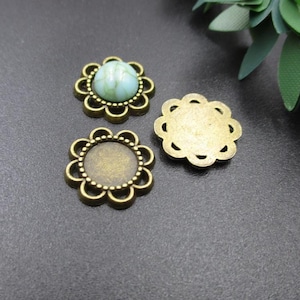 Może przedstawiać: Trzy antyczne, złocone metalowe oprawy w kształcie kwiatu do kaboszonów. Jedna oprawa ma jasnozielony kaboszon.