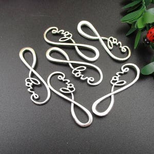 May include: Six silver metal charms shaped like infinity symbols with the word "love" inscribed on each charm.