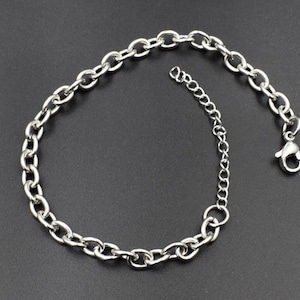 May include: A silver chain necklace with a lobster clasp closure. The chain is made of thick, oval-shaped links.