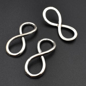 May include: Three silver infinity symbol charms, each with a smooth, polished finish. These charms are perfect for adding a touch of elegance to jewellery projects.