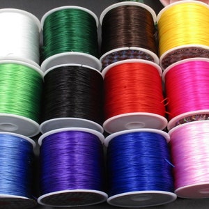 May include: Spools of colorful elastic string in various colors, including white, green, brown, yellow, black, red, pink, blue, purple, and light blue.