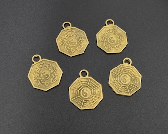 May include: Five gold-colored metal charms with a yin yang symbol in the center. Two charms feature a dragon design, and three charms feature a circular design with lines radiating from the center.