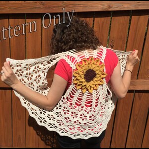 May include: A crochet vest with a sunflower design on the back. The vest is white and has a scalloped edge. The sunflower is yellow with a brown centre.