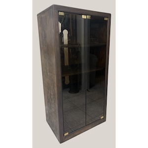 May include: A dark wood cabinet with glass doors and brass accents. The cabinet has two shelves and is perfect for displaying items.