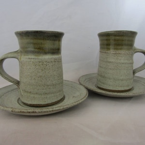 A pair of Studio pottery coffee cups with saucer in matte white and gloss green glazes