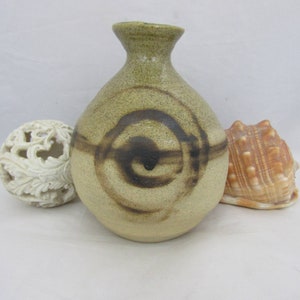 May include: A small, round, ceramic vase with a brown and tan swirl design. The vase has a narrow neck and a wide base.