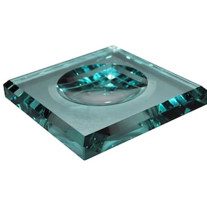 以下が含まれることがあります： 正方形のターコイズブルーのガラス製の皿で、中央が丸く少しへこんでいます。皿は斜めにカットされた縁を持っています。