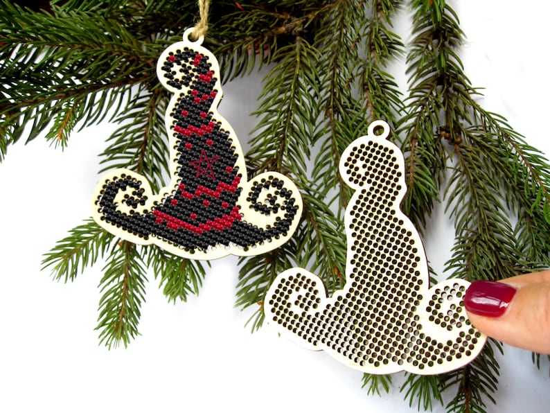 May include: Two unfinished wooden Christmas ornaments shaped like a witch's hat and a cat. The ornaments are ready to be decorated with embroidery floss.