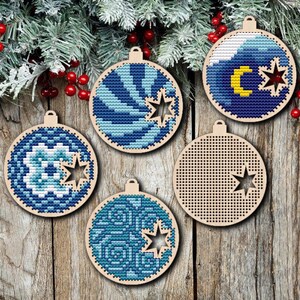 Könnte beinhalten: Fünf hölzerne Weihnachtskugeln mit blauen und weißen Stickereien. Die Kugeln zeigen einen Halbmond, Sterne und geometrische Muster.