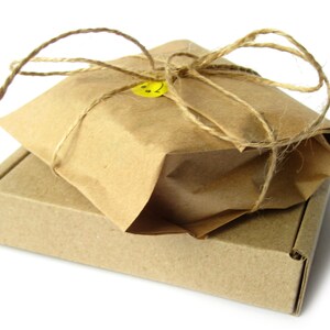 May include: A brown cardboard box with a brown paper package on top. The package is tied with twine and has a yellow smiley face sticker.