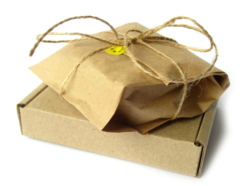 May include: A brown cardboard box with a brown paper package on top. The package is tied with twine and has a yellow smiley face sticker.