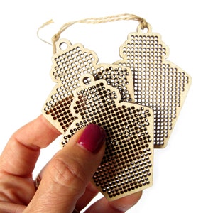 May include: Three unfinished wooden ornaments shaped like bottles with a grid pattern for cross-stitch embroidery.
