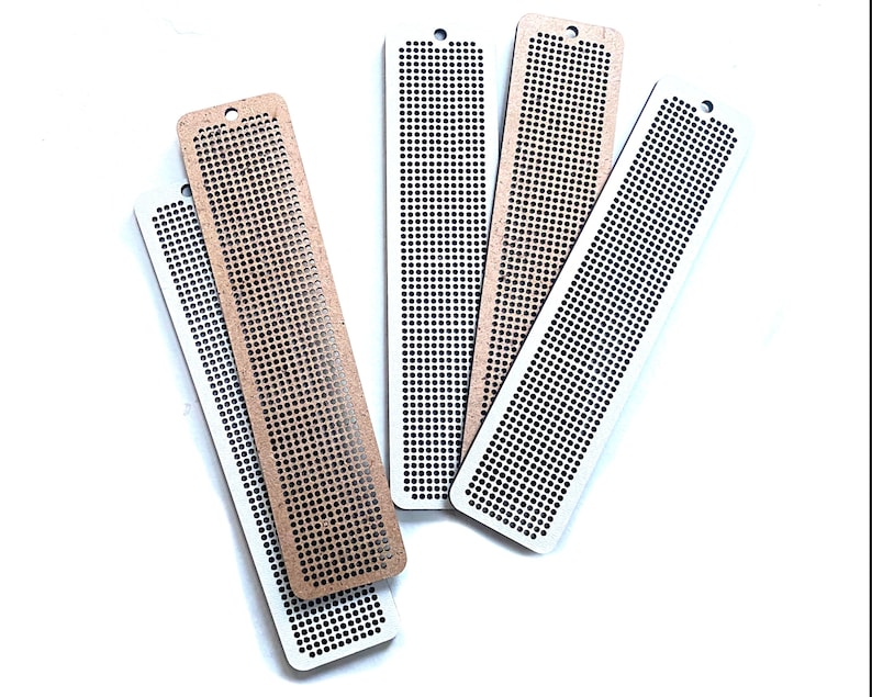 Peut inclure: Cinq marque-pages en bois avec un motif en grille. Les marque-pages sont de deux couleurs&nbsp;: marron et blanc. Les marque-pages ont un trou en haut pour les suspendre.