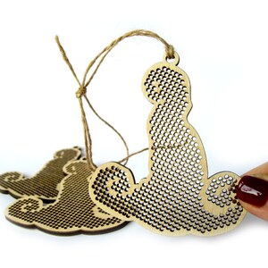 May include: Three unfinished wooden ornaments shaped like a bear, with a grid pattern for cross-stitching. The ornaments are strung together with twine.