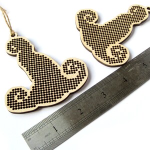 May include: Two unfinished wooden ornaments shaped like a seahorse, each with a hole for hanging. The ornaments are approximately 2 inches tall and are shown next to a ruler.