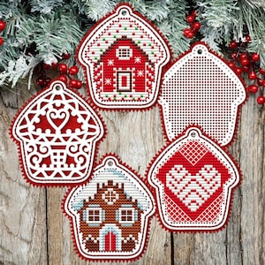Puede incluir: Un conjunto de adornos navideños con forma de casas de jengibre. Los adornos son rojos y blancos con varios diseños, incluyendo un corazón, una casa con una puerta y una casa con ventanas. Los adornos cuelgan de una cuerda.