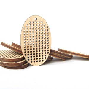 May include: A stack of oval-shaped wooden embroidery hoops with a grid pattern of holes. The hoops are made of light brown wood and are arranged in a staggered pattern.
