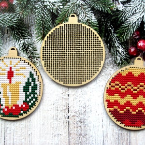 May include: Three round wooden ornaments with a Christmas theme. One ornament has a red and gold design, one has a candle and greenery design, and one is blank.